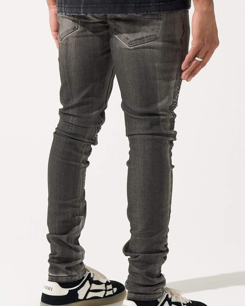 Person wearing dark gray jeans and black and white shoes on a white background