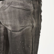 Close-up of dark gray jeans with rhinestone embellishments on a white background