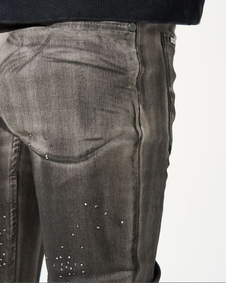 Close-up of dark gray jeans with rhinestone embellishments on a white background