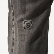 Close-up of a dark gray denim fabric with a brand logo on a white background