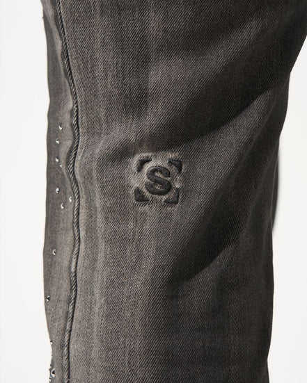 Close-up of a dark gray denim fabric with a brand logo on a white background