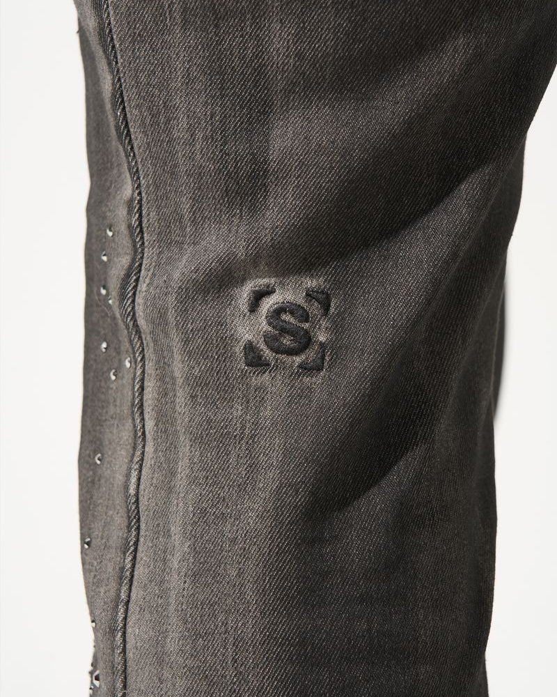 Close-up of a dark gray denim fabric with a brand logo on a white background