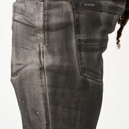 Close-up of dark gray jeans with a brand label on a white background
