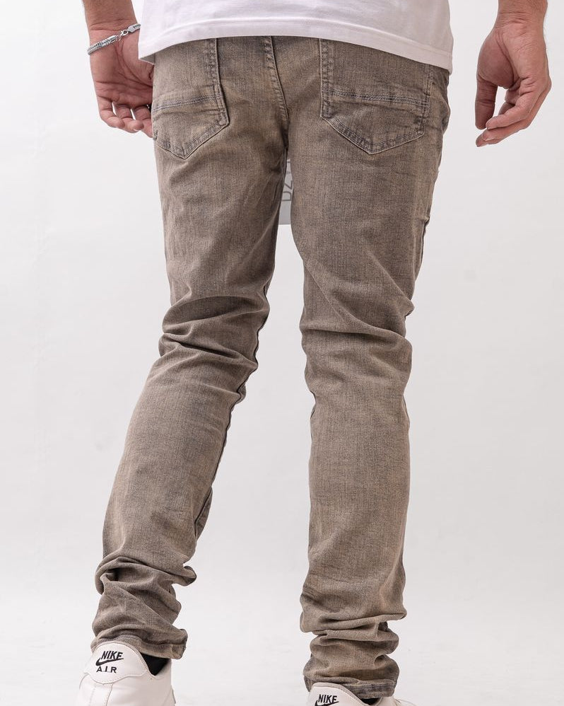 Person wearing brown jeans and white sneakers on a white background