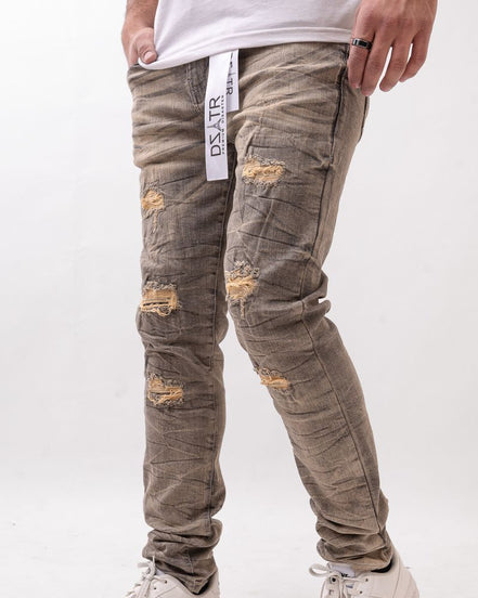 Person wearing distressed gray jeans with a white background