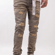 Person wearing distressed gray jeans with a visible brand label on a white background