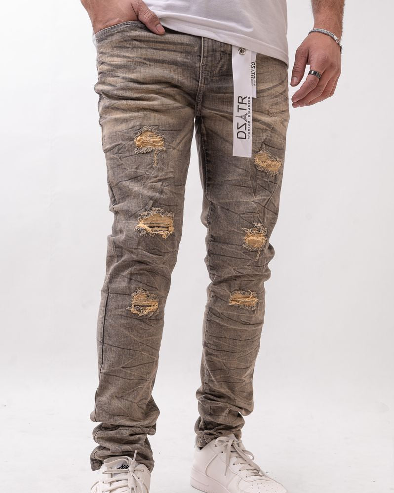 Person wearing distressed gray jeans with a visible brand label on a white background