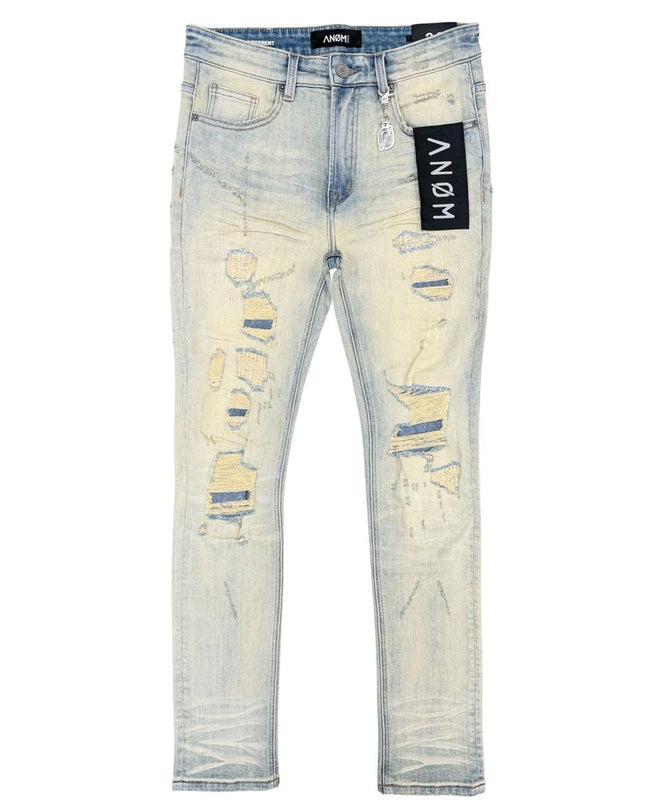 Light wash distressed skinny jeans with ripped details on the thighs and knees, featuring a black ANOM brand tag on the pocket.