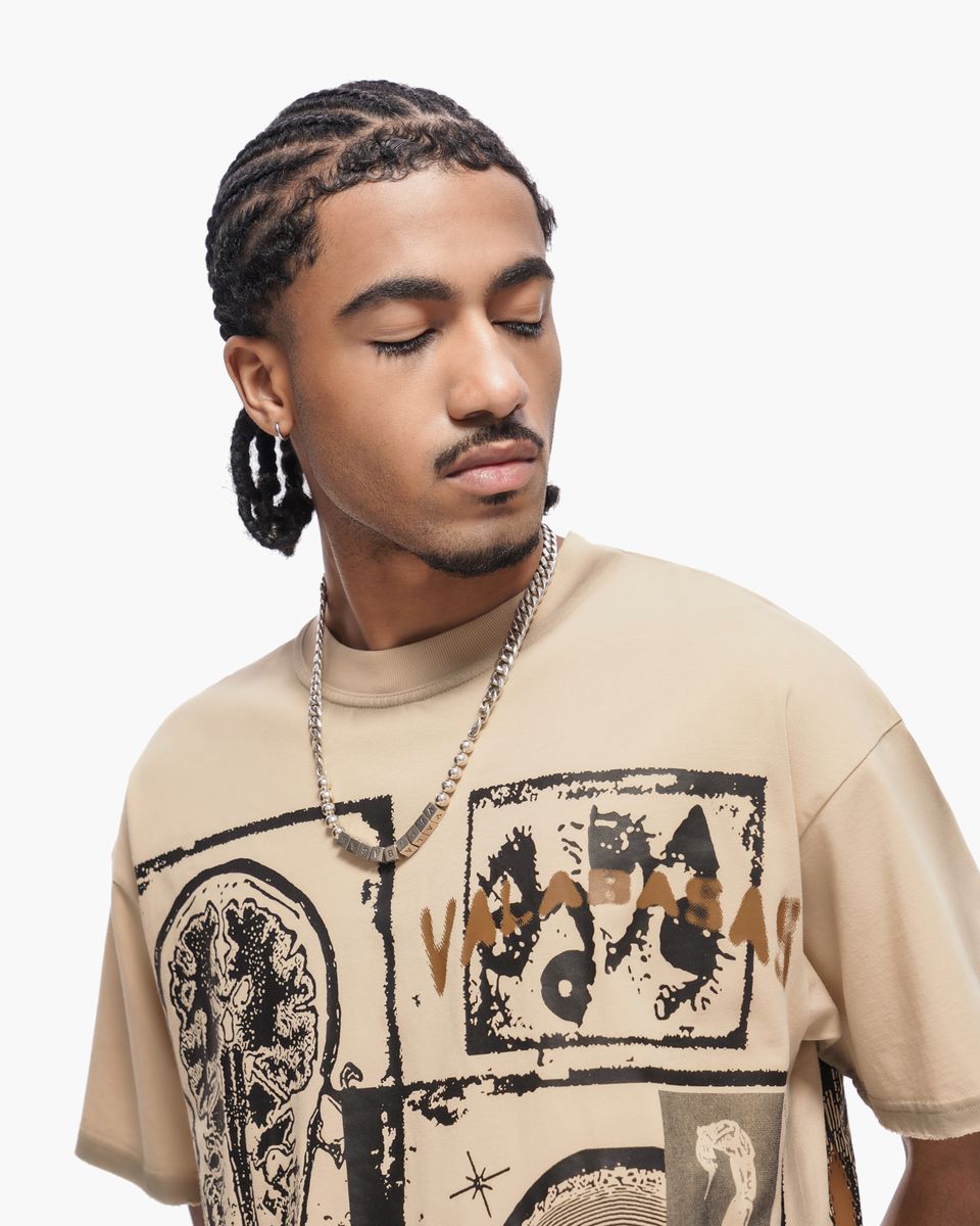 Man wearing a beige t-shirt with graphic designs on a white background