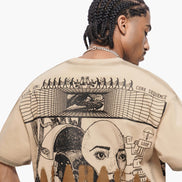 Person wearing a beige t-shirt with intricate black graphics on the back