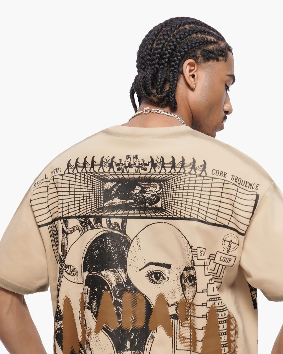 Person wearing a beige t-shirt with intricate black graphics on the back