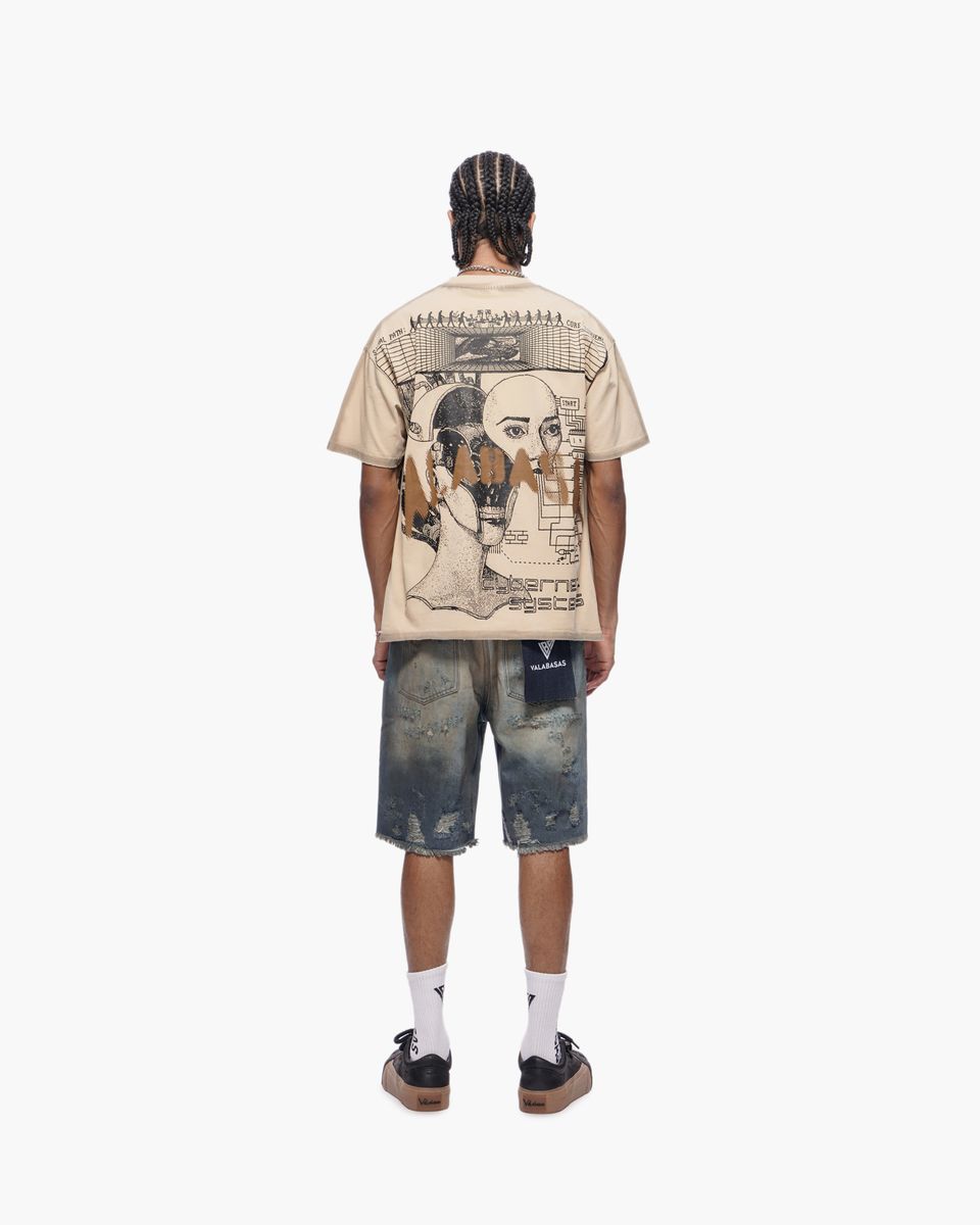 Person wearing a beige t-shirt with graphic design and distressed blue shorts on a white background