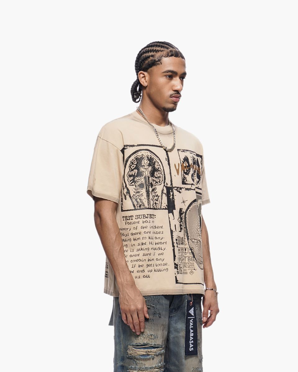 Man wearing a beige t-shirt with graphic design and text, standing against a white background