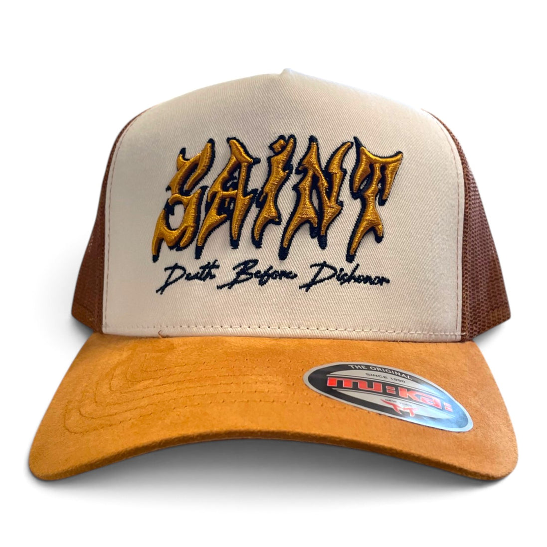 A beige and brown trucker hat with 'SAINT' embroidered in a gold and black gothic font on the front, with 'Death Before Dishonor' stitched below. The brim is a warm tan suede, and the back panels are beige mesh with brown side panels.
