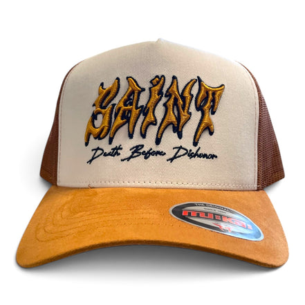 A beige and brown trucker hat with 'SAINT' embroidered in a gold and black gothic font on the front, with 'Death Before Dishonor' stitched below. The brim is a warm tan suede, and the back panels are beige mesh with brown side panels.