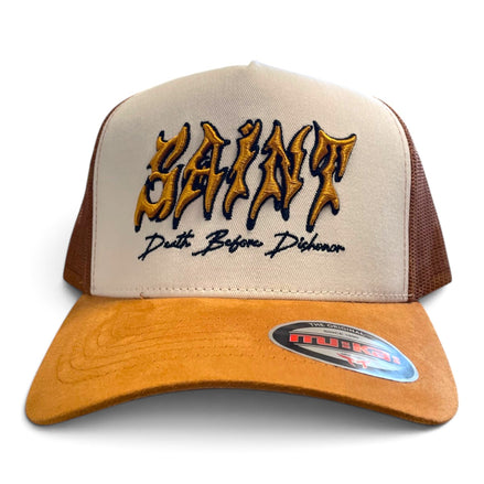 A beige and brown trucker hat with 'SAINT' embroidered in a gold and black gothic font on the front, with 'Death Before Dishonor' stitched below. The brim is a warm tan suede, and the back panels are beige mesh with brown side panels.