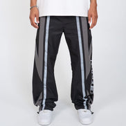 Black track pants with gray stripes worn by a person on a white background