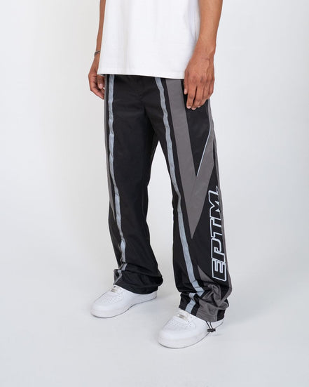 Person wearing black and gray pants with a logo on a white background