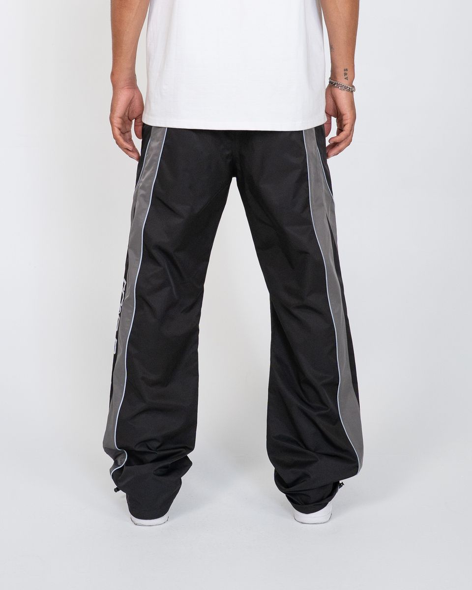 Black pants with gray stripes worn by a person on a white background