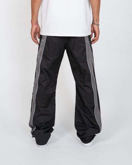 Black pants with gray stripes worn by a person on a white background