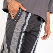 Gray athletic pants with white stripes worn by a person on a white background