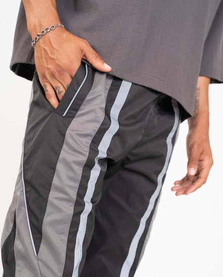 Gray athletic pants with white stripes worn by a person on a white background