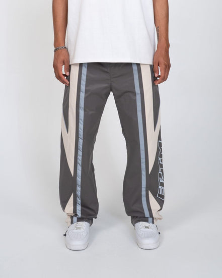 Person wearing gray pants with white and IRRIDESCENT stripes on a white background