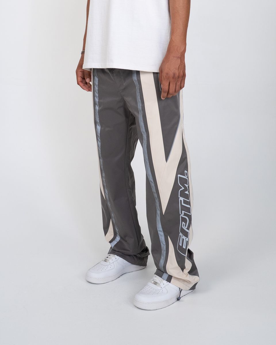 Person wearing gray pants with a geometric pattern and white sneakers on a white background