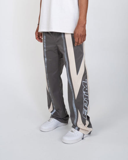 Person wearing gray pants with a geometric pattern and white sneakers on a white background