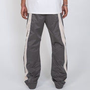Person wearing gray track pants with white stripes on a white background