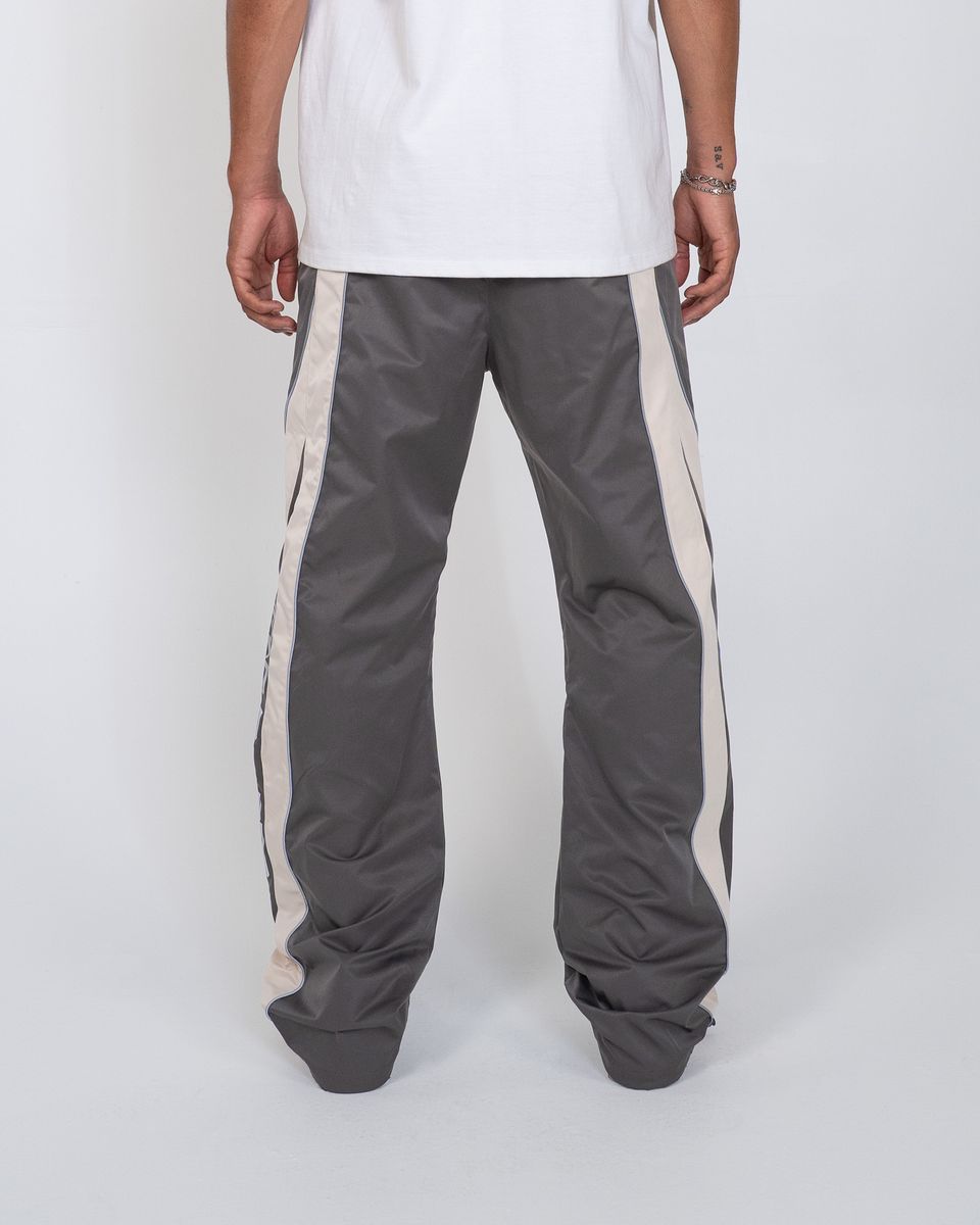 Person wearing gray track pants with white stripes on a white background