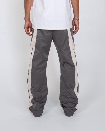 Person wearing gray track pants with white stripes on a white background