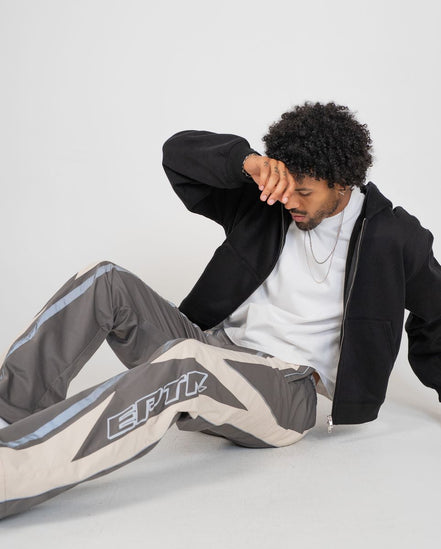 Person wearing a black jacket and gray pants with 'EPTM' branding on a white background