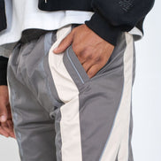 Person wearing gray and white pants with a black jacket on a light gray background