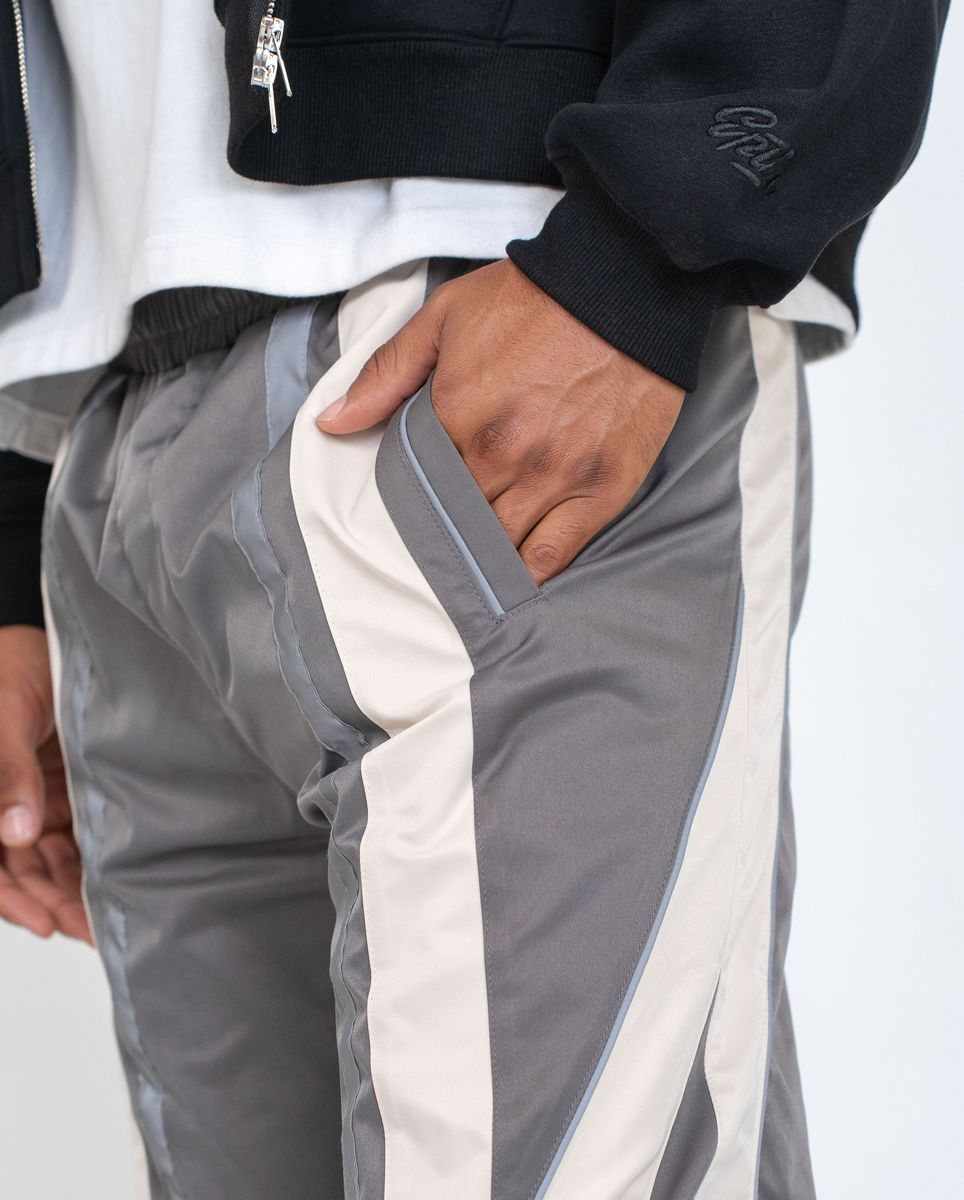 Person wearing gray and white pants with a black jacket on a light gray background