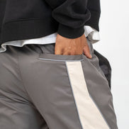 Gray pants with a white stripe worn by a person on a light gray background