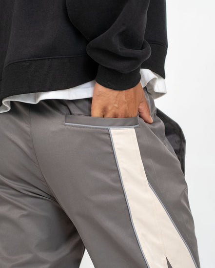 Gray pants with a white stripe worn by a person on a light gray background