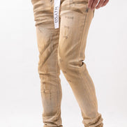 Beige distressed jeans worn by a person on a white background