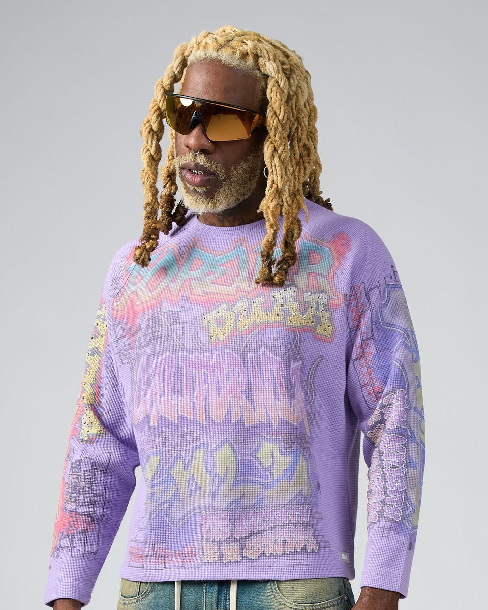 Person wearing a purple graphic sweatshirt with colorful text and designs on a plain background