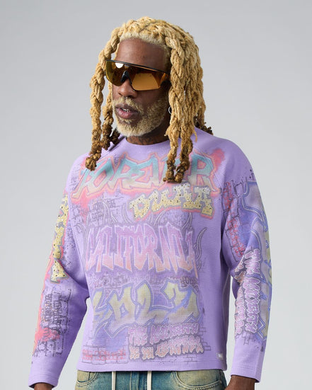 Person wearing a purple graphic sweatshirt with colorful text and designs on a plain background