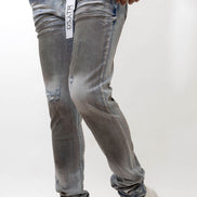 Person wearing distressed blue-gray jeans with a visible brand logo on a white background
