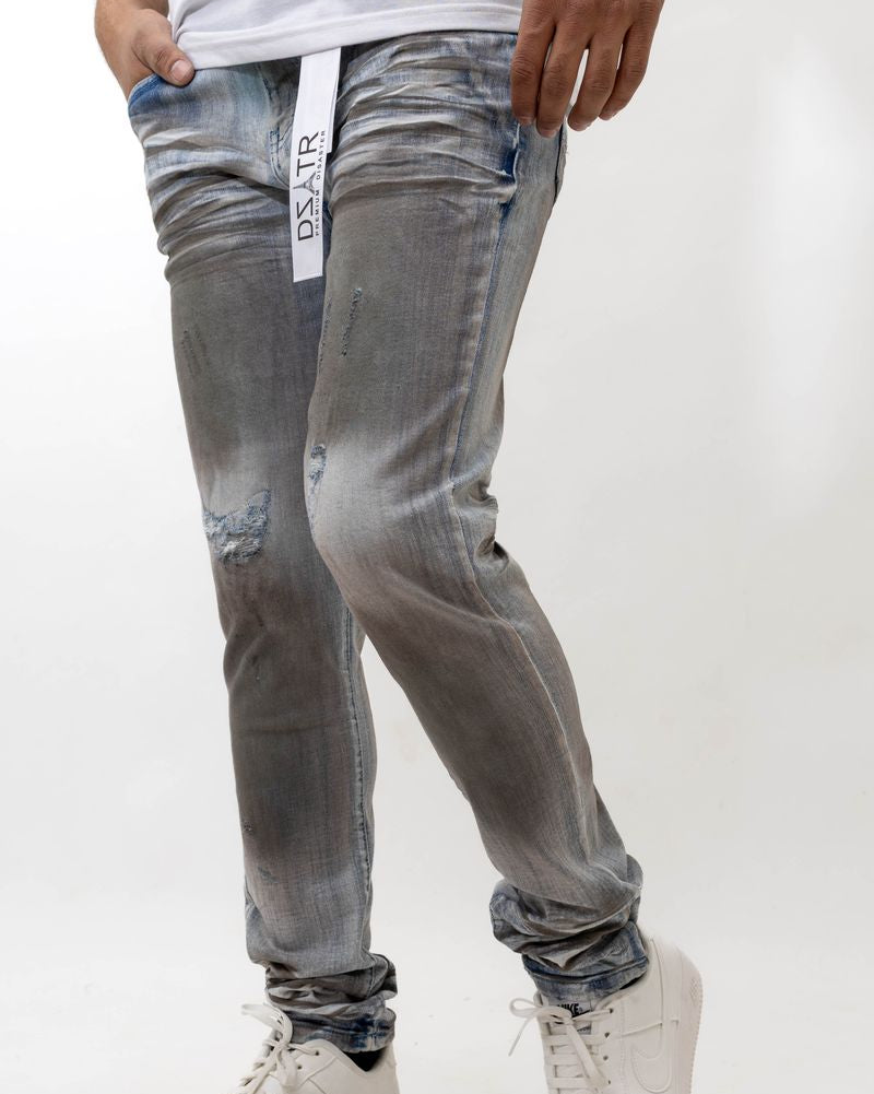 Person wearing distressed blue-gray jeans with a visible brand logo on a white background