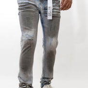Person wearing distressed gray jeans with a visible brand label on a white background