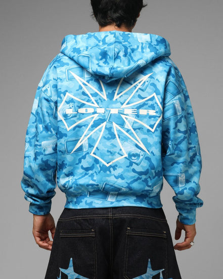 Blue camouflage hoodie with a brand logo on the back, worn by a person against a gray background.