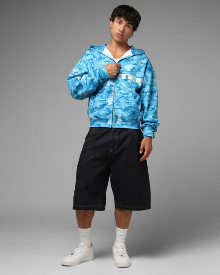 Person wearing a blue camouflage hoodie and black shorts on a gray background