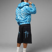 Person wearing a blue tie-dye hoodie and black shorts with blue designs on a gray background