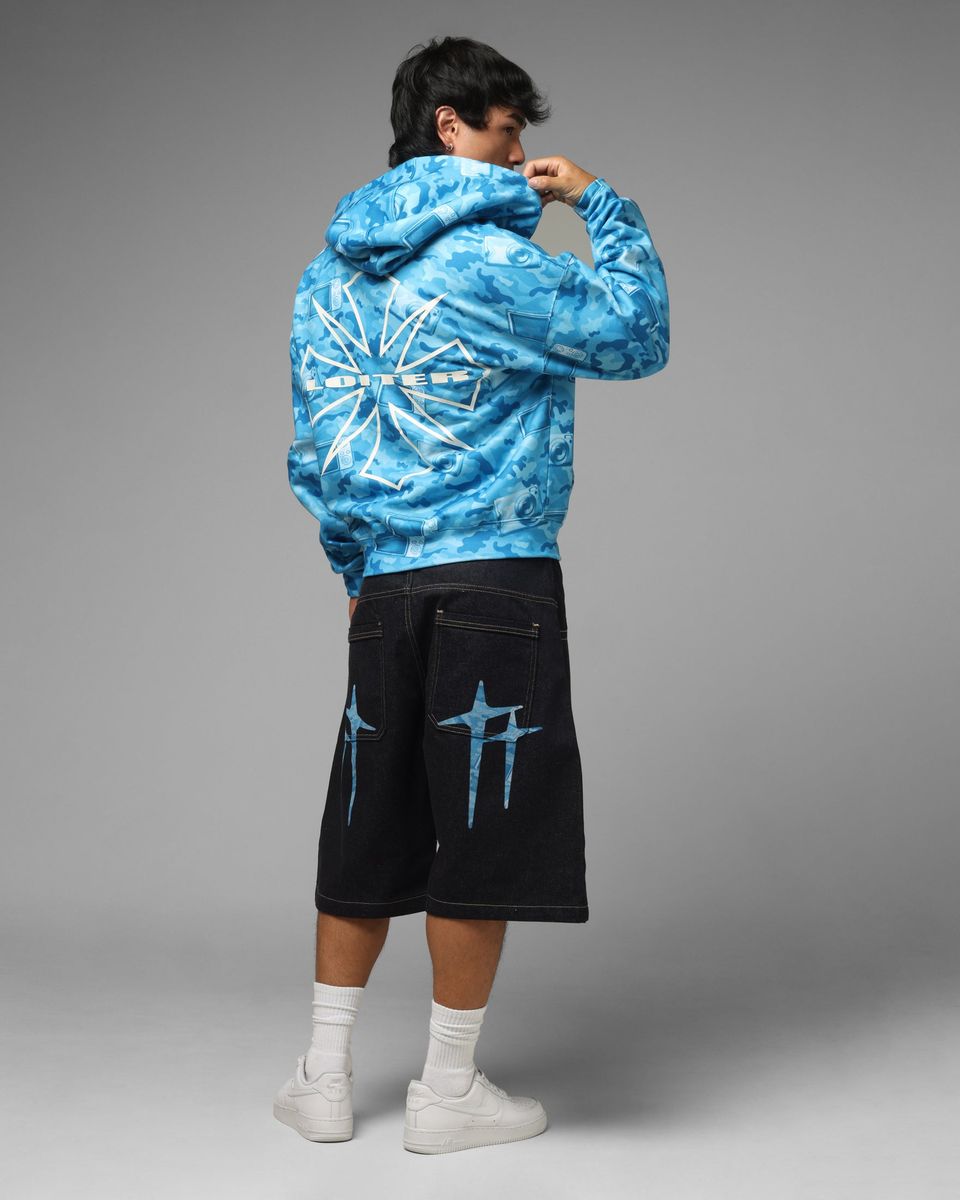 Person wearing a blue tie-dye hoodie and black shorts with blue designs on a gray background