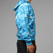 Person wearing a blue camouflage hoodie on a gray background