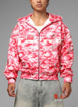 Person wearing a pink camouflage jacket with brand logos on a gray background