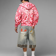 Person wearing a pink and white tie-dye hoodie and gray shorts with a brand logo on a gray background